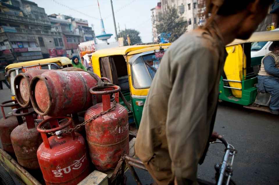 Gas tanks are being transported by a human rickshaw in New Delhi