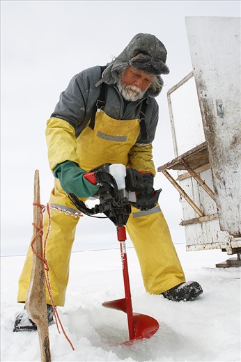 Frank Kenyon cuts a hole with an auger into the ice of Lake Manitoba.