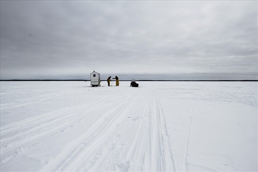 Fishermen draw in one of their nets. They and use a heated hut for shelter.