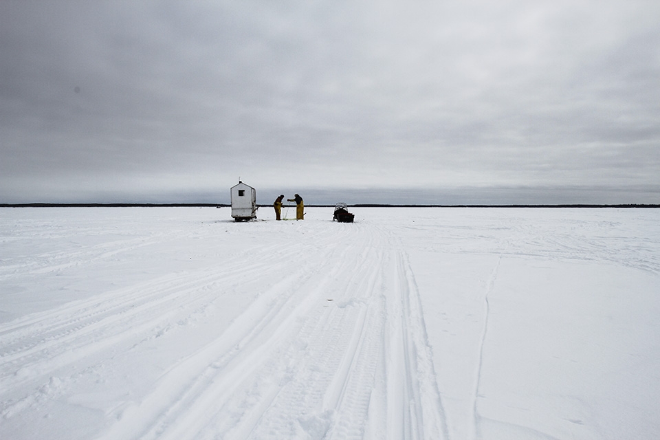 Fishermen draw in one of their nets. They and use a heated hut for shelter.
