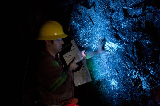 Geologist Ehsan Salmabadi shows off glowing tungsten deposits in the rock face