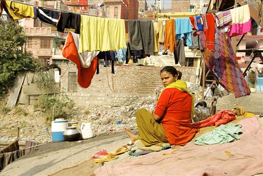 From her cement perch overlooking the railroad tracks, a woman waits for dishes and laundry to dry.