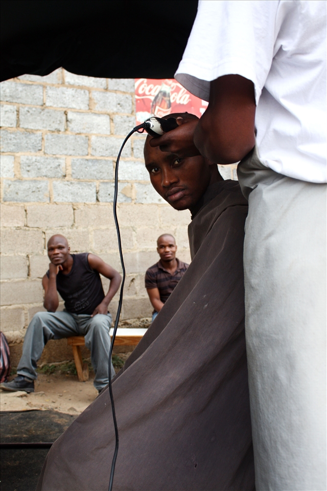  As the barber sterilizes his shears in turpentine, jobless men start to gather