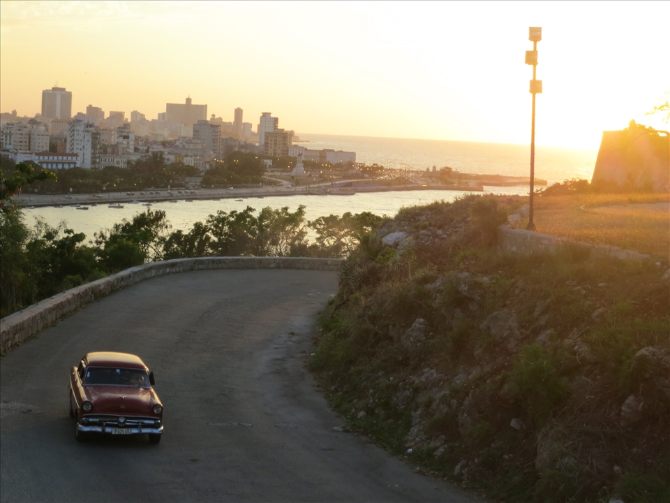 A View to the Past: Havana is a city of many contradictions. Yet, when you travel there is feels as if you are suddenly transported back in time to the 50's, surrounded by old American cars and crumbling buildings. This picture signifies the old world feeling of the city, combining both the old cars and the old city in the background. The golden glow from the sun setting makes it looks at if the photo is as old as everything in it. The picture was taken from the Christ Statue on the hill above Casablanca across Havana Harbour from the city. 