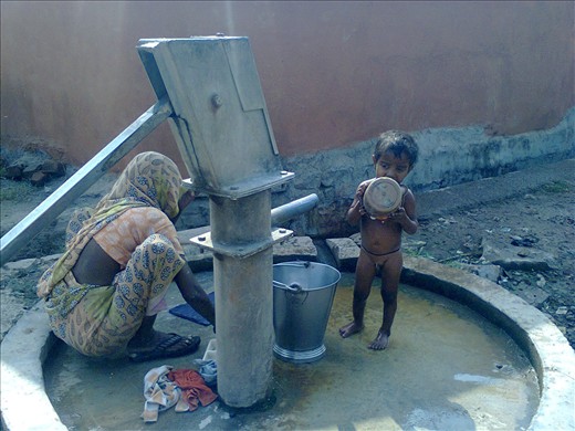 Mother and child at hand pump at a village, Indoore, India.