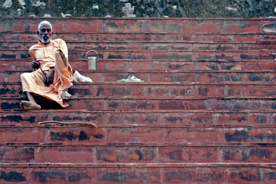 An ascetic man rests on steps lining the river Ganges. Such men live a life of severe self-discipline and abstention from all forms of indulgence.