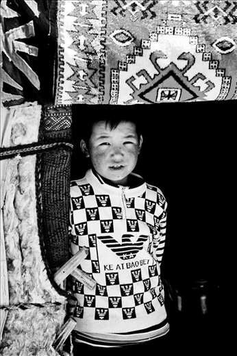 A Kyrgyz boy stands in the doorway of his family's yurt, waiting for visiters. 