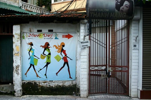Advertisment and entrance to a beauty parlor. The doorsign says already welcome even the door is still closed. However the girls are rushing in already.