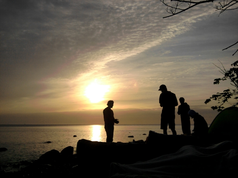 As the sun goes down friends are united in the nature, preparing firewood for survival. We only have each other.