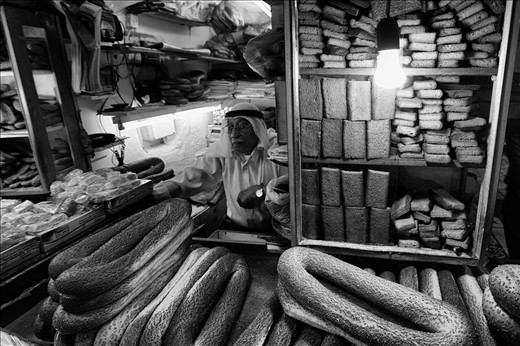 An elderly man sells the distinctive ‘sesame round bread’ at his stall in the Souk of the Muslim Quarter, Jerusalem. The Old City of Jerusalem is home to a some of the holiest sites in the world for Jews, Muslims, and Christians alike. This can lead to tension between the inhabitants, with the surrounding area of East Jerusalem playing host to the hugely controversial barrier wall that separates Israel from the Palestinian West Bank. 
