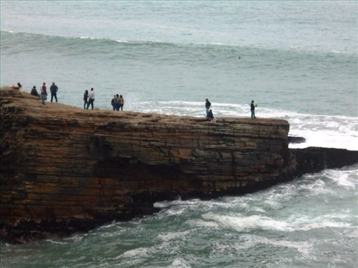 Cliff for the men to jump off into the sea below. There is a rope dangling down for them to climb back up again. 