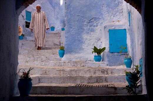 Dressed in his traditional Moroccan dress, a djellaba, this man walks through the maze of predominately blue and white alleyways that make up the Mountain town of Chefchaouen, a popular tourist destination in Morocco.  The locals go about their business as though the thousands of tourists do not exist.
