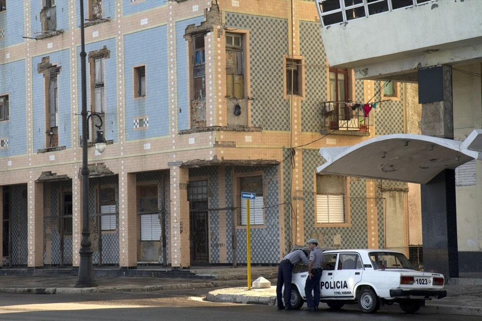 Here we see two police men standing beside their broken down police vehicle in a empty Havana street. A heavy police presence on the streets and harsh prison sentences have been major deterrents for criminals. As a result crime rates in Cuba remain significantly lower than in many other large cities worldwide.