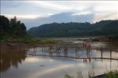 Monks walk across a bamboo bridge over a tributary to the Mekong. Monks walk across a bamboo bridge over a tributary to the Mekong.