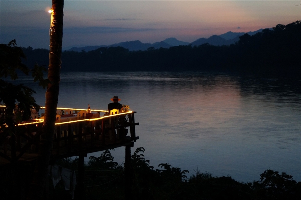 A man winds down in a restaurant overlooking the Mekong. Strict development regulations a midnight curfew maintain the relaxed character of Luang Prabang, which gained UNESCO World Heritage Site status in 1995.