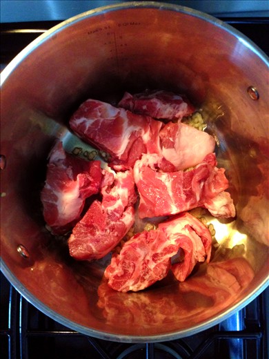 Begin the sauce by simmering the pork neck bones in olive oil & garlic .