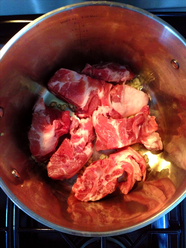 Begin the sauce by simmering the pork neck bones in olive oil & garlic .