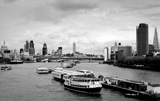 Great skyline of the London city with river boats and barges running along or parked there.