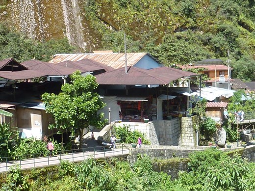 The mountains are rising up behind the houses.  If the river doesn't get them the mountain slips may.