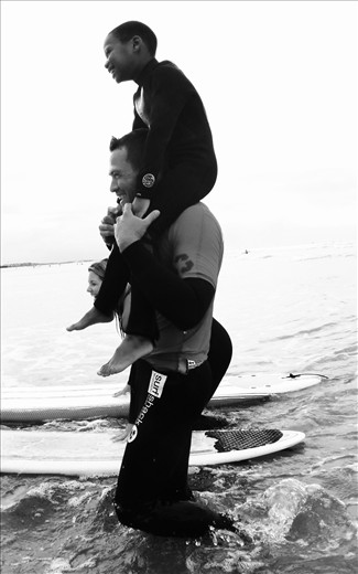 DTR Volunteers teaching a young boy Thio, to Surf for the First time