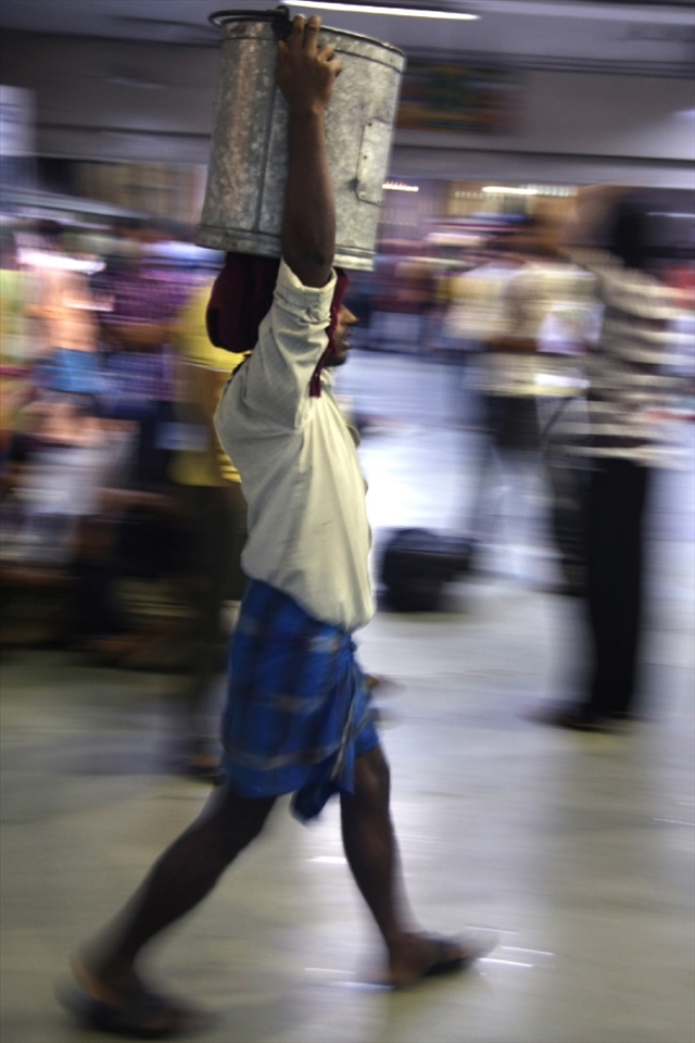 
Waiting for the Darjeeling Mail at Kolkata's Sealdah station, the atmosphere is hectic, as people run from one side to another. Here a man transports a container of food to a soon-to-depart train.