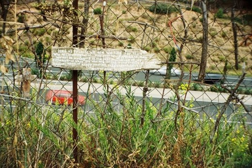 A poem written onto a piece of wood, stuck into the fence near a busy motorway.