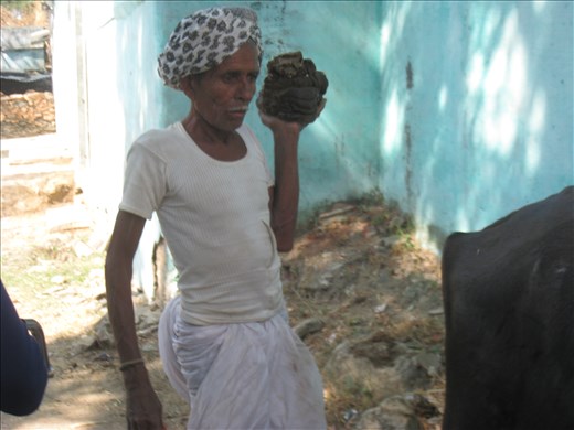 man carrying cow dung to patch up his wall