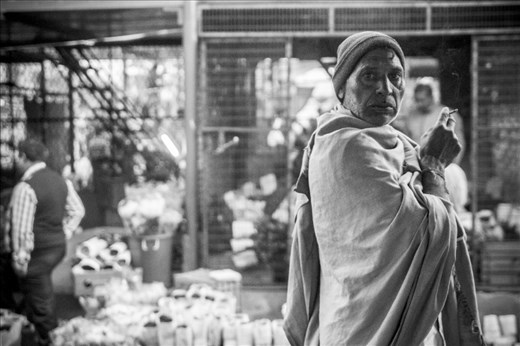 Hugging his shawl tight against the winter, this flower walla observes Mandi life with a smoke.