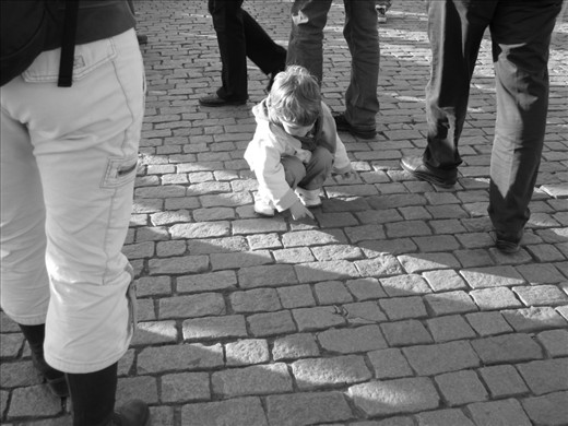 Not even a tourist would most likely find the Old Town's cobblestones quite as interesting. A child stops to examine the shapes in the street as those older and more experienced rush on past. A woman appears to stop and watch--the mother? A bystander? The question is if she will find beauty now that she's begun to look.  