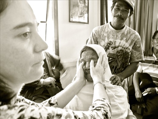 An old wooden structure in Sukadana Borneo houses ASRI Medical Clinic. Dr. Kinari Webb feels around for hardening of the eye balls on an 88-year-old woman.  One of her sons places his hand on her shoulders, offering her some comfort.  Due to clogging of the drainage canals, increased pressure leads to irreversible damage to the optic nerve, resulting in blindness.  If caught early, glaucoma can be treated by medications and laser surgeries. But more often than not, glaucoma isn’t properly diagnosed.  Unfortunately this woman has advanced glaucoma and will sadly remain blind for the rest of her life. 