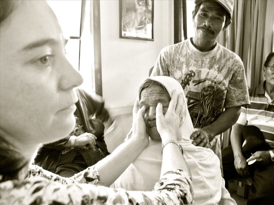 An old wooden structure in Sukadana Borneo houses ASRI Medical Clinic. Dr. Kinari Webb feels around for hardening of the eye balls on an 88-year-old woman.  One of her sons places his hand on her shoulders, offering her some comfort.  Due to clogging of the drainage canals, increased pressure leads to irreversible damage to the optic nerve, resulting in blindness.  If caught early, glaucoma can be treated by medications and laser surgeries. But more often than not, glaucoma isn’t properly diagnosed.  Unfortunately this woman has advanced glaucoma and will sadly remain blind for the rest of her life. 