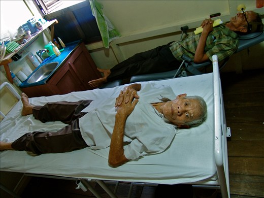One of four rooms in the long house is converted into a pre surgery room.  Bapak Wanji (forefront) waits to receive a retrobulbar injection before he goes in for cataract surgery. Retrobulbar is used as an anesthetic but it is also prevents the globe of the eye from moving around during surgery.  A tennis ball helps to soften the eye just after injection.  