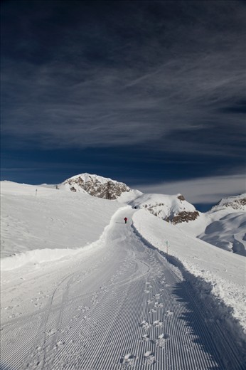 I was attempting to discover the mountains beyond the ski resort in Val D'isere, France. I had taken the ski lift up Le Fornet and had taken the hikers path over the mountain. As I passed a man, I turned around to watch his ascent up the path. There were no skis here. I don't know where he came from or where he was going but I was compelled to take his photograph as he continued his journey round the mountain. 