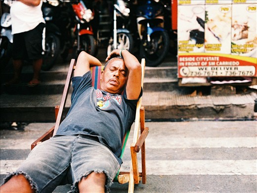 A man has his siesta in the middle of a bustling city. 