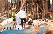 Everyone has their own role to play in the fishing ‘production line’ in the village and here the boys are busy untangling and mending the fishing nets.  In the background the stilt legs of the houses tower above the boat. : by katpayne, Views[387]