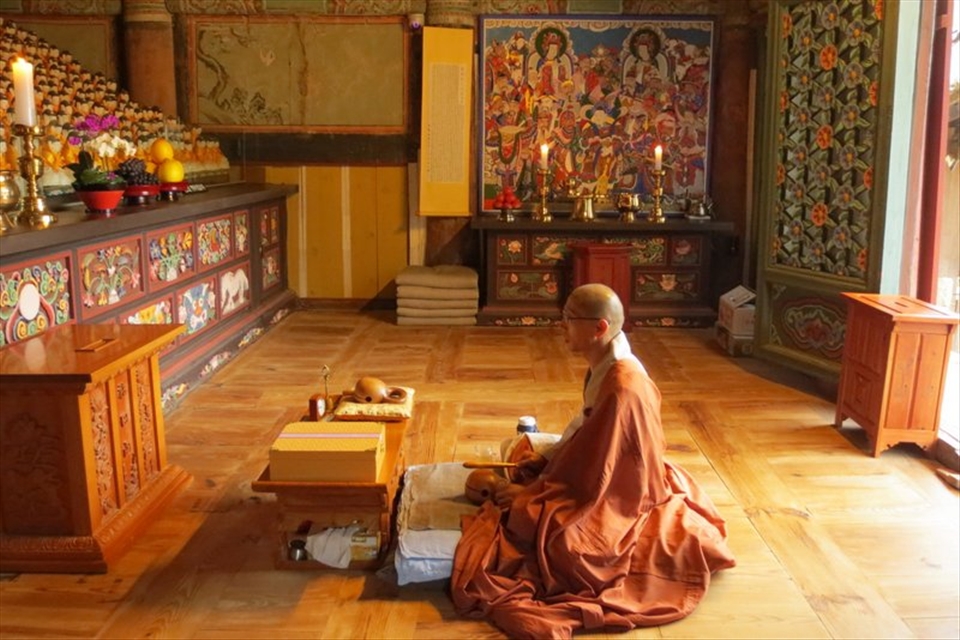 A Buddhist monk at Daeheungsa Temple in a room with hundreds of small Buddhas