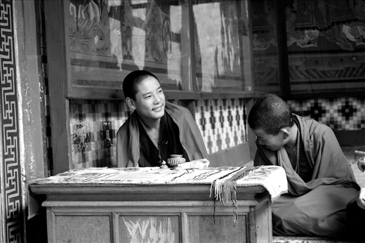 Young monks at Paro Monastery - Two young monks, selling religious amulets and lucky charms, laugh at something my mother asked them. Usually very shy, especially when surrounded by women who point cameras at them, these two couldn't resist after a few minutes of us imploring them to answer a few questions that they thought were absolutely unnecessary or were not difficult enough to be questions. Monk training is very gruelling and requires a great amount of strength. Even the Dalai Lama once admitted he wanted to run away during the course of his monk education. So it is very rare to see them laugh like this, especially the younger ones.