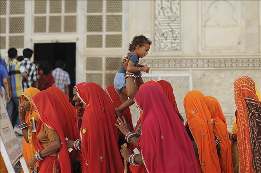 A boy is raised high in the air by his mother with a group of Indian tourists waiting in line to go inside the Taj Mahal mausoleum.