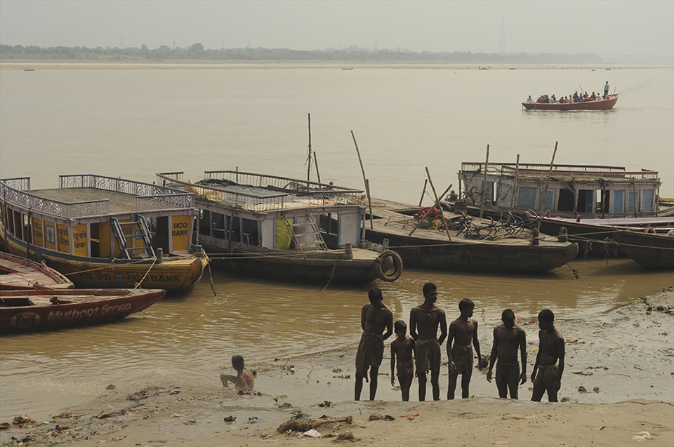 During a really heavy rain in Varanasi, a group of boys were scouring the riverbank of Ganga for whatever they can find useful that were washed off by the water current from the city. After the treasure hunt, the boys somehow gathered up. It's quite curious what they're up to, probably concerning how each other did on their hunt. 