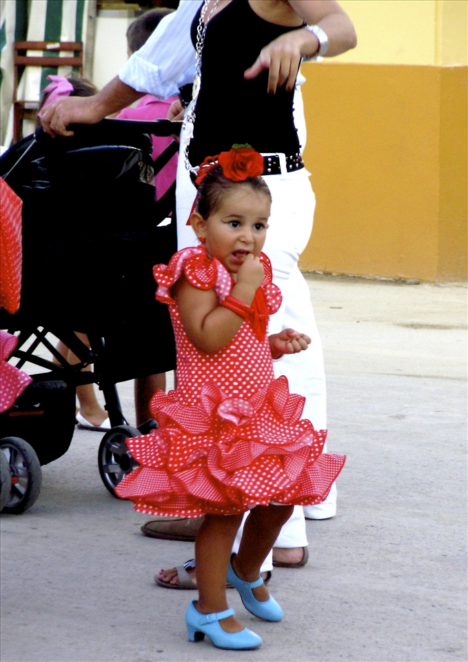 (3) A girl nervously prepares for a day of Flamenco dancing at the fair. The style of traditional dance originated in the province of Andalucía, where Cádiz is located.