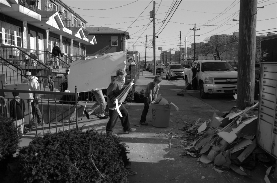 Rockaway Beach, NY: A man loaded up the back of a pickup truck with his children and drove back to his ruined house, where they blasted classic rock at a high enough volume for all the neighbors to come out and smile as they saw his troop of children taking out rotten pieces of sheetrock and wood. Hurricane Sandy caused over $63 billion USD in damage across the United States when it struck on October 2012.