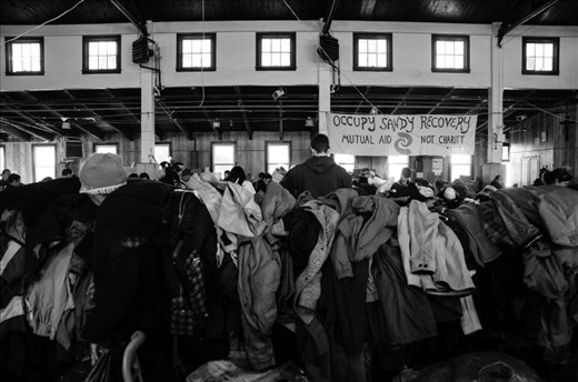 Rockaway Beach, NY: Tables at St. Camillus School are overflowing with clothing provided by donations. The gymnasium doors were open for residents and suppliers alike. Trucks constantly pulled in and out of the street, with cadres of men and women of all ages hauling boxes of supplies inside. Occupy Sandy as well as FEMA were able to provide material assistance, but for most, it's not enough. Jose Marrero, a resident of Rockaway Beach, is among the many. 