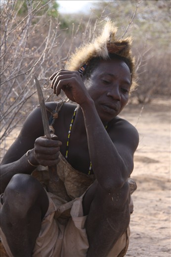 The tribesmen wait patiently to carve the Dik Dik on the fire.