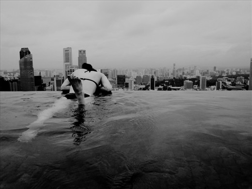 a girl looking down the city from the pool at the top of the hotel, Marina Bay Sands, in Singapore.
