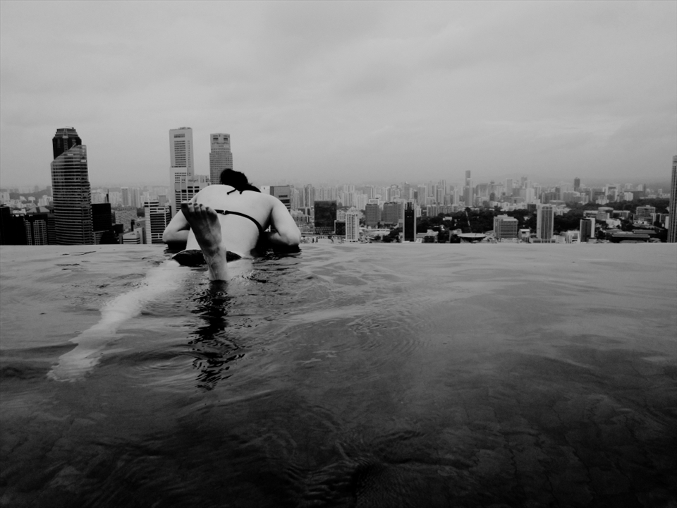 a girl looking down the city from the pool at the top of the hotel, Marina Bay Sands, in Singapore.