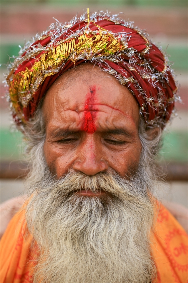 A baba sitting at one of the many ghats near the river resting his eyes for a moment of respite. 