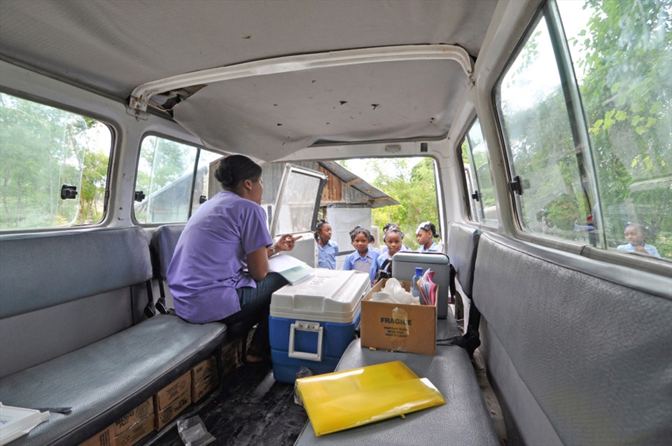 Haiti is an incredibly mountainous country with comparably few roads to rural and remote areas, an element that makes access to health care difficult. To combat this problem, organizations use mobile clinics—cars packed full of supplies and medical professionals who travel to remote catchment areas to provide counsel, education and medicine, among other things. This photo shows just that: a community health nurse instructing school girls on how—and when—to take the vitamins they're receiving. 