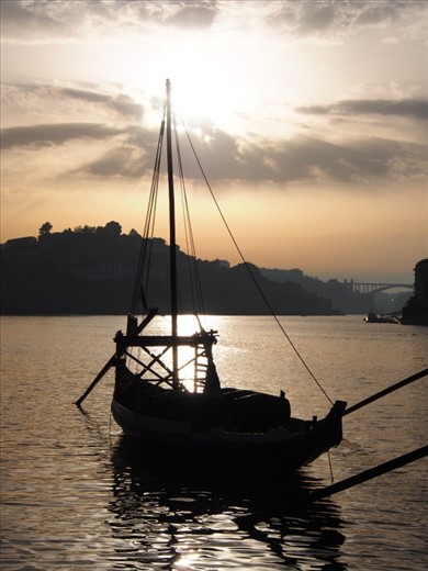 Sun setting on a fading tradition of transportation on the Douro River bathed in golden light giving strength to its name de-ouro, the river of gold.