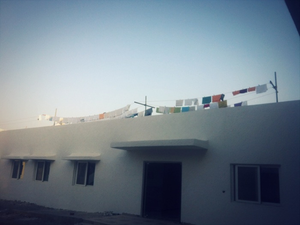 A construction worker's home and their laundry under the clear sky.