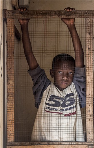 sad eyed African boy inside his father's corner store in Serrekunda, The Gambia
